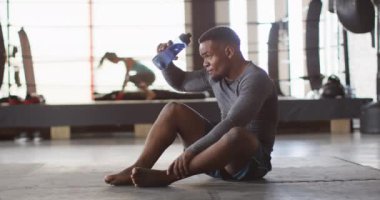 Spor salonundaki eğitimden sonra dinlenen sağlıklı ve yorgun Afrikalı Amerikalı adamın videosu. aktif, formda, sportif ve sağlıklı yaşam tarzı, spor konsepti egzersizi.