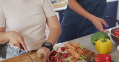 Mutlu kadın çift sebze pişiriyor ve mutfakta kucaklaşıyorlar. evde kaliteli zaman geçirmek.