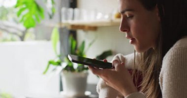 Beyaz, çift cinsiyetli olmayan, akıllı telefondan konuşan bir kadın. Evde yalnız geçirilen kaliteli zaman, bedensel kapsama..