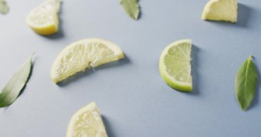 Mavi arka planda duran limon dilimleri ve nane yapraklarının videosu. yiyecek, meyve, narenciye, ferahlatıcı ve ferahlatıcı konsept.