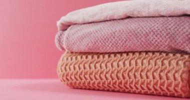 Pembe arka planda yatan katlanmış battaniyelerin videosu. Kumaş, tekstil, ev tasarımı ve konforu.