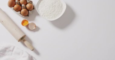 Beyaz yüzeyde duran malzemelerin ve aletlerin videosu. Pişirme, yemek hazırlama, tat ve lezzet kavramı.