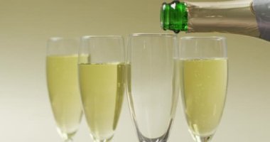 Video of champagne pouring into glasses on yellow background. alcohol, beverage, drinks, party and celebration concept.