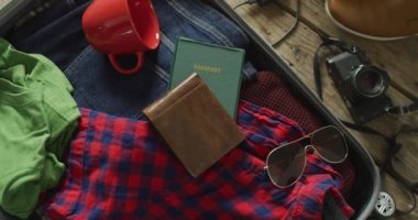 Video of documents, glasses, camera, mug and clothes prepared to be packed in suitcase for travel. traveling, holidays and vacation concept,