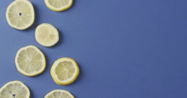 Mavi arka planda duran ve fotokopi alanı olan limon dilimlerinin videosu. yiyecek, meyve, narenciye, ferahlatıcı ve ferahlatıcı konsept.