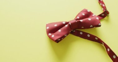 Sarı arka planda duran kırmızı noktalı papyonun videosu. Erkekler moda, kıyafetler, aksesuarlar ve zarafet konsepti.