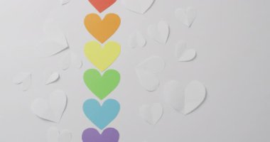 Beyaz arka planda duran renkli kağıt kalplerin videosu. Gay gururu, lgbt hakları ve azınlık konseptini destekleme.