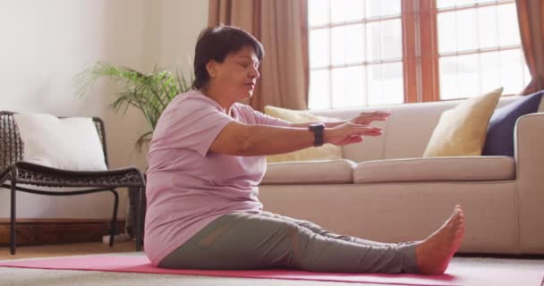 自宅でヨガマットに座ってストレッチ運動を行うアジアのシニア女性 退職生活と生活の概念 — ストック動画