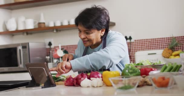 Mujer Mayor Asiática Que Usa Tableta Digital Mientras Corta Verduras — Vídeos de Stock