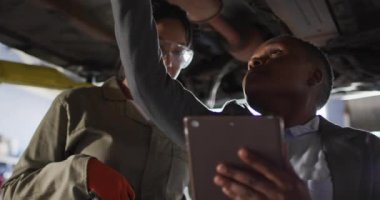 İki farklı kadın araba tamircisi ve tablet kontrol arabalı iş sahibinin videosu. Araba tamirhanesinde çalışmak ve küçük kadınsı iş konsepti yürütmek..