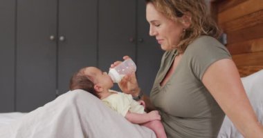 Kafkasyalı mutlu bir annenin yeni doğan bebeği şişeyle beslediği video. annelik, ebeveyn sevgisi ve yeni doğan bebek konseptiyle ilgilenmek dijital olarak üretilmiş video.