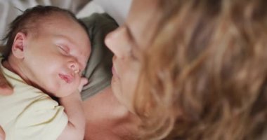 Kafkasyalı mutlu bir annenin uyuyan yeni doğmuş bir bebekle yatakta yattığı video. annelik, ebeveyn sevgisi ve yeni doğan bebek konseptiyle ilgilenmek dijital olarak üretilmiş video.