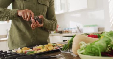 Türbanlı bir kadının yemek hazırlayıp biber eklediği orta bölüm videosu. Yaşam tarzı, yemek pişirme, ev konseptinde boş zaman geçirme..
