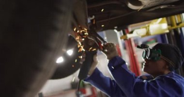 Amerikalı kadın araba tamircisinin öğütücü kullandığını gösteren bir video. Araba tamirhanesinde çalışmak ve küçük kadınsı iş konsepti yürütmek..