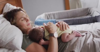 Kafkasyalı mutlu bir annenin uyuyan yeni doğmuş bir bebekle yatakta yattığı video. annelik, ebeveyn sevgisi ve yeni doğan bebek konseptiyle ilgilenmek dijital olarak üretilmiş video.