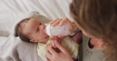 Kafkasyalı mutlu bir annenin yeni doğan bebeği şişeyle beslediği video. annelik, ebeveyn sevgisi ve yeni doğan bebek konseptiyle ilgilenmek dijital olarak üretilmiş video.