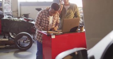 Dizüstü bilgisayar ve akıllı telefon kullanarak araba parçaları arayan iki farklı kadın araba tamircisinin videosu. Araba tamirhanesinde çalışmak ve küçük kadınsı iş konsepti yürütmek..
