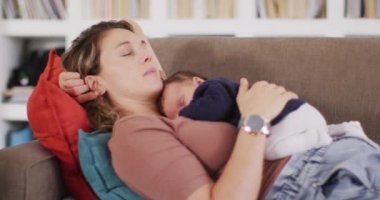 Yeni doğmuş bebekle uyuyan yorgun beyaz bir annenin videosu. annelik, ebeveyn sevgisi ve yeni doğan bebek konseptiyle ilgilenmek dijital olarak üretilmiş video.