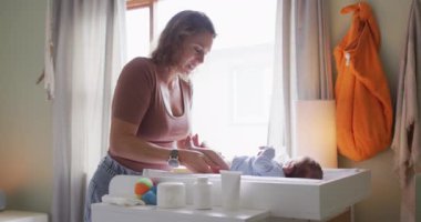 Yeni doğan bebeği değiştiren mutlu beyaz bir annenin videosu. annelik, ebeveyn sevgisi ve yeni doğan bebek konseptiyle ilgilenmek dijital olarak üretilmiş video.