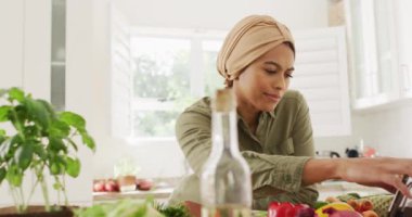 Mutfakta akıllı telefon kullanan tesettürlü mutlu kadın videosu. Yaşam tarzı, yemek pişirme, ev konseptinde boş zaman geçirme..