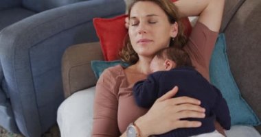 Yeni doğmuş bebekle uyuyan yorgun beyaz bir annenin videosu. annelik, ebeveyn sevgisi ve yeni doğan bebek konseptiyle ilgilenmek dijital olarak üretilmiş video.