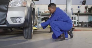 Afrika asıllı Amerikalı kadın araba tamircisinin lastik değiştirdiği bir video. Araba tamirhanesinde çalışmak ve küçük kadınsı iş konsepti yürütmek..