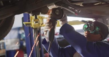 Amerikalı kadın araba tamircisinin öğütücü kullandığını gösteren bir video. Araba tamirhanesinde çalışmak ve küçük kadınsı iş konsepti yürütmek..