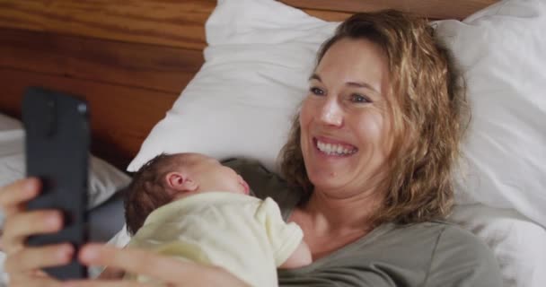 Wideo Szczęśliwej Białej Matki Leżącej Łóżku Śpiącym Noworodkiem Korzystającej Smartfona — Wideo stockowe