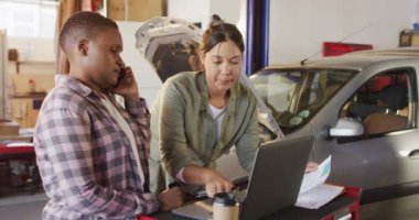 Dizüstü bilgisayar ve akıllı telefon kullanarak araba parçaları arayan iki farklı kadın araba tamircisinin videosu. Araba tamirhanesinde çalışmak ve küçük kadınsı iş konsepti yürütmek..
