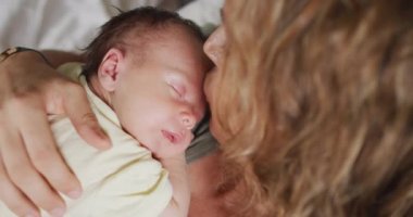 Kafkasyalı mutlu bir annenin uyuyan yeni doğmuş bir bebekle yatakta yattığı video. annelik, ebeveyn sevgisi ve yeni doğan bebek konseptiyle ilgilenmek dijital olarak üretilmiş video.