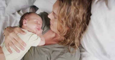 Kafkasyalı mutlu bir annenin uyuyan yeni doğmuş bir bebekle yatakta yattığı video. annelik, ebeveyn sevgisi ve yeni doğan bebek konseptiyle ilgilenmek dijital olarak üretilmiş video.