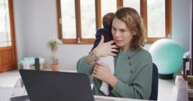 Beyaz bir annenin yeni doğmuş bir bebekle dizüstü bilgisayarla çalıştığı bir video. annelik, ebeveyn sevgisi ve yeni doğan bebek konseptiyle ilgilenmek dijital olarak üretilmiş video.