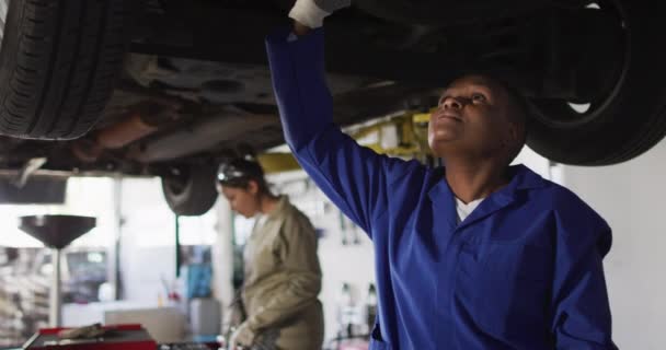 アフリカ系アメリカ人女性の車整備士のチェック車のビデオ 車修理工場で働き女性らしい小さなビジネスコンセプトを運営しています — ストック動画
