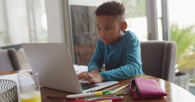 Video of african american boy doing homework. Childhood, education, learning and spending time at home concept.