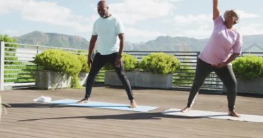 Video of happy african american couple exercise on the terrace. Senior lifestyle, retirement lifestyle, active leisure time.