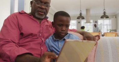 Afrika kökenli Amerikalı büyükbaba ve torununun birlikte tablet kullandıkları video. Aile, birlikte zaman geçirme kavramı..
