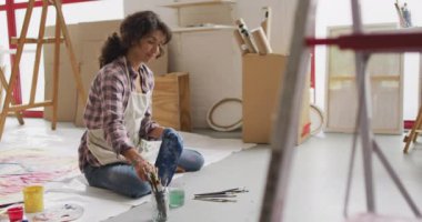 Stüdyoda yerde resim yapan iki ırklı kadın ressamın videosu. Sanat, el sanatları, yaratıcılık ve yaratılış süreci kavramı.