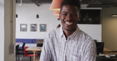 Ofiste kameraya bakan mutlu Afro-Amerikan iş adamının portresi. Modern bir ofiste çalışıyorum..