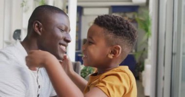 Video of happy african american father and son hugging at home. Family, spending quality time together at home concept.