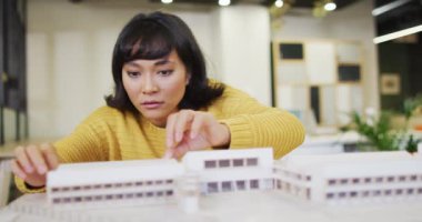 Çift ırklı iş kadını masada oturuyor ve ofiste mankenlerle çalışıyor. Modern bir ofiste çalışıyorum..