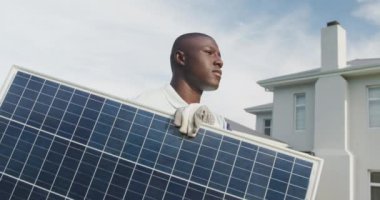 Güneş paneli tutan Afro-Amerikan bir adamın videosu. Güneş enerjisi, yeşil güç ve eko yaşam tarzı kavramı.