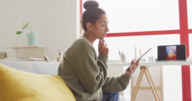 Video of happy biracial female designer using tablet in studio. Art, crafts, creativity, creation process and running own business concept.