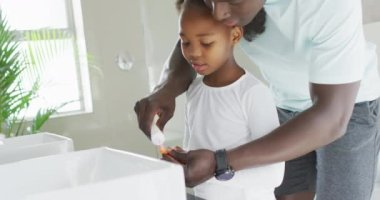  african american father and daughter brushing teeth. Enjoying quality family time together at home.
