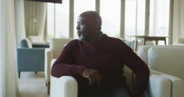 Video of thoughtful senior african american men sitting in living room alone. Retirement lifestyle, spending time alone.