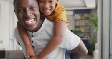 Video of happy african american father and son hugging at home. Family, spending quality time together at home concept.