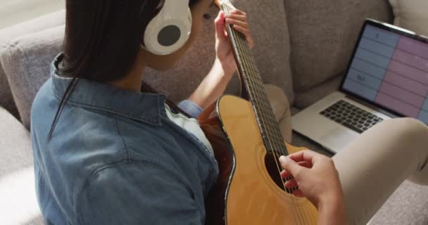 Video Happy Biracial Woman Headphones Sitting Sofa Playing Guitar Lifestyle — 图库视频影像