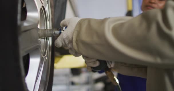 Video Hands Biracial Female Car Mechanic Changing Tyre Working Car — стоковое видео