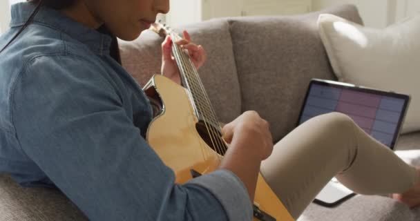Video Happy Biracial Woman Headphones Sitting Sofa Playing Guitar Lifestyle — Vídeo de Stock