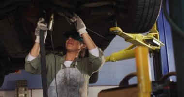 Video of biracial female car mechanic welding car. Working in car repair shop and running small feminine business concept.