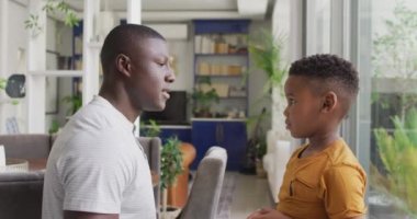 Video of happy african american father and son hugging at home. Family, spending quality time together at home concept.